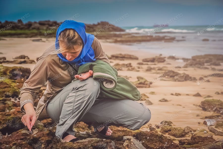 عکس زن در حال جمع آوری صدف در ساحل
