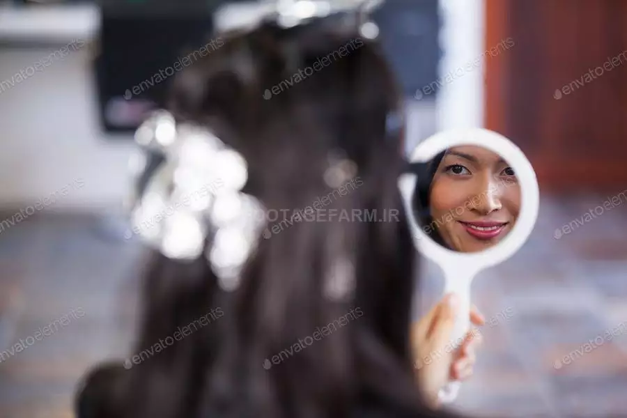 عکس زن در حال نگاه کردن به خود در آینه