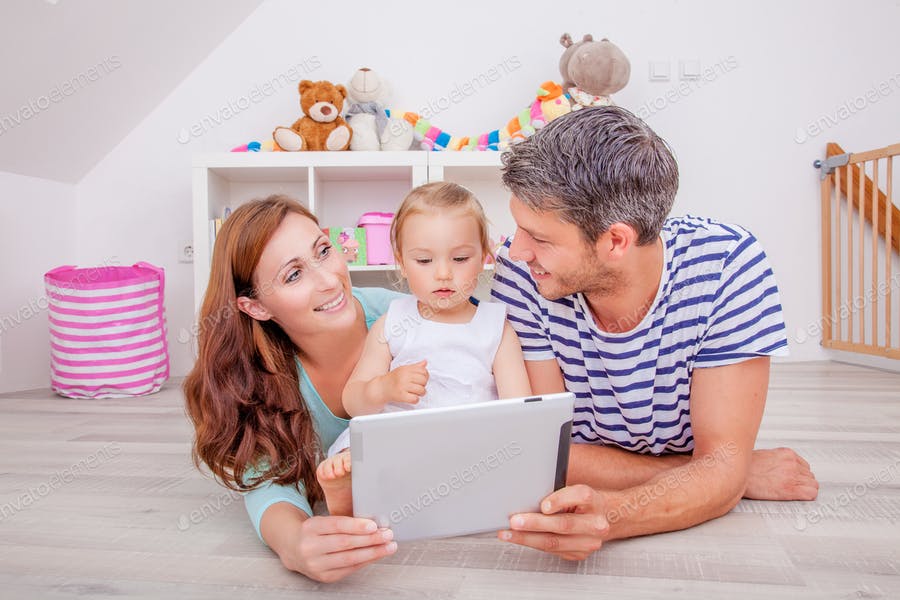 عکس مادر و پدر در حال تماشای کارتون با نوزاد