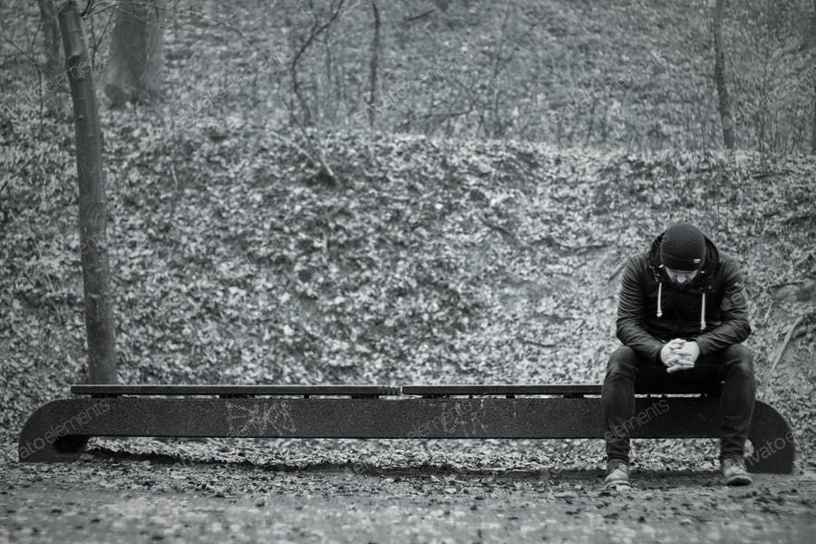 عکس مرد غمگین نشسته روی صندلی پارک